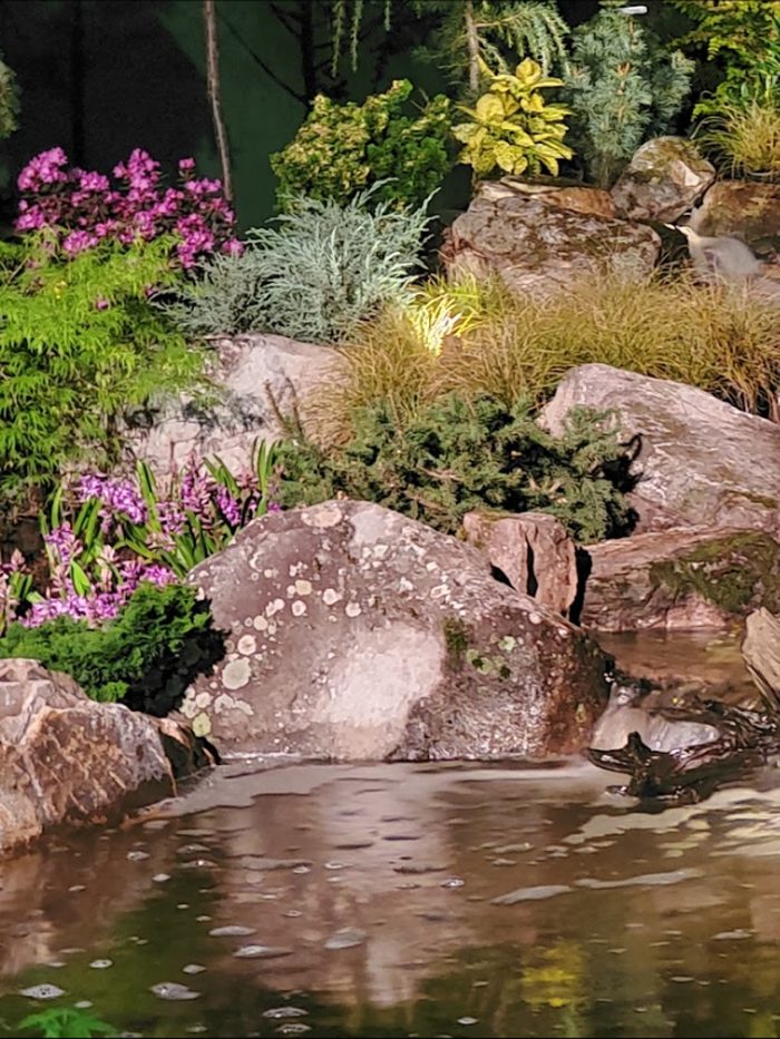 Boulders meeting azaleas and ornamental grasses at the water's edge