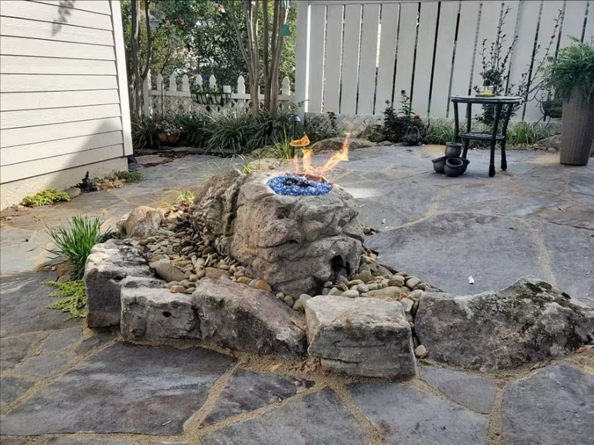 Boulder fire feature set into a flagstone patio