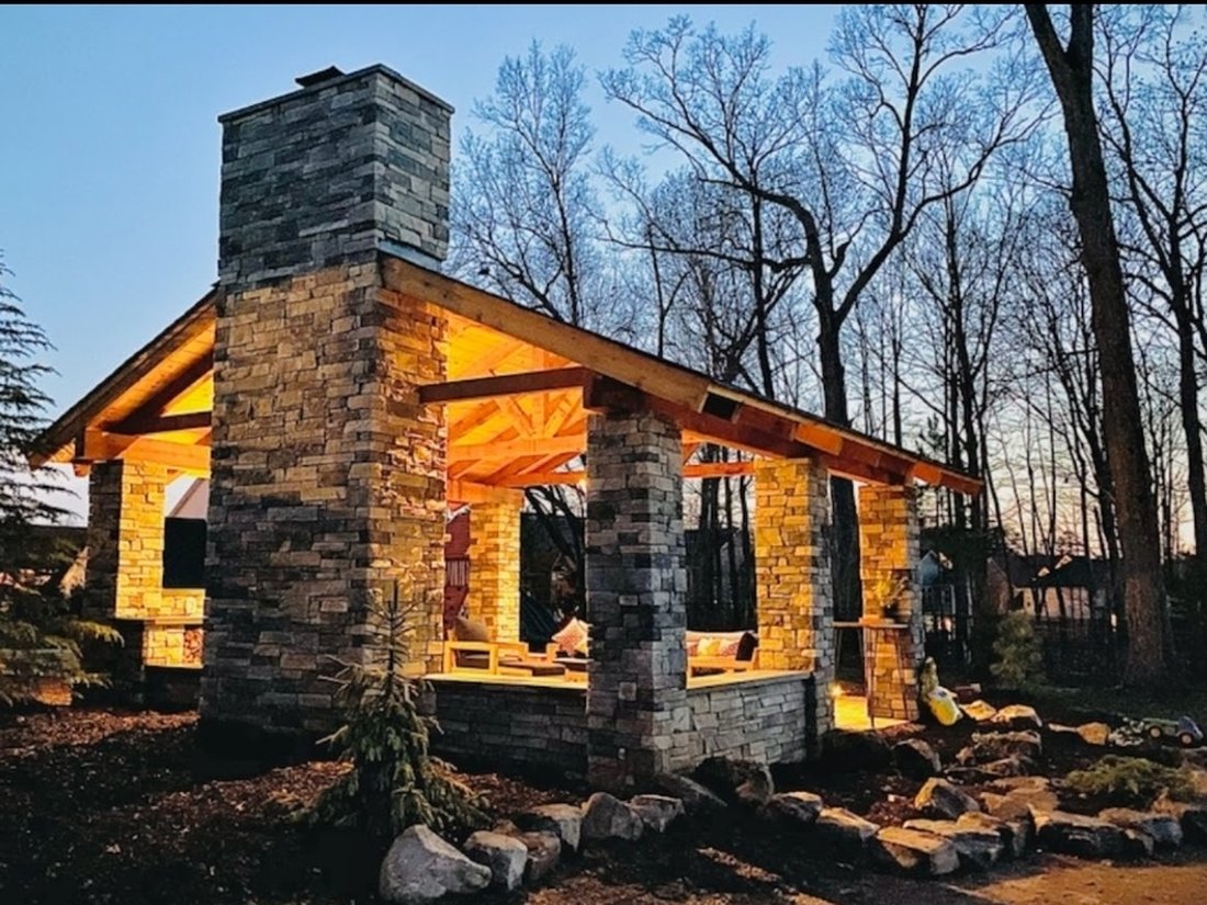 Stone-and-timber pavilion with joinery detail, lit at twilight