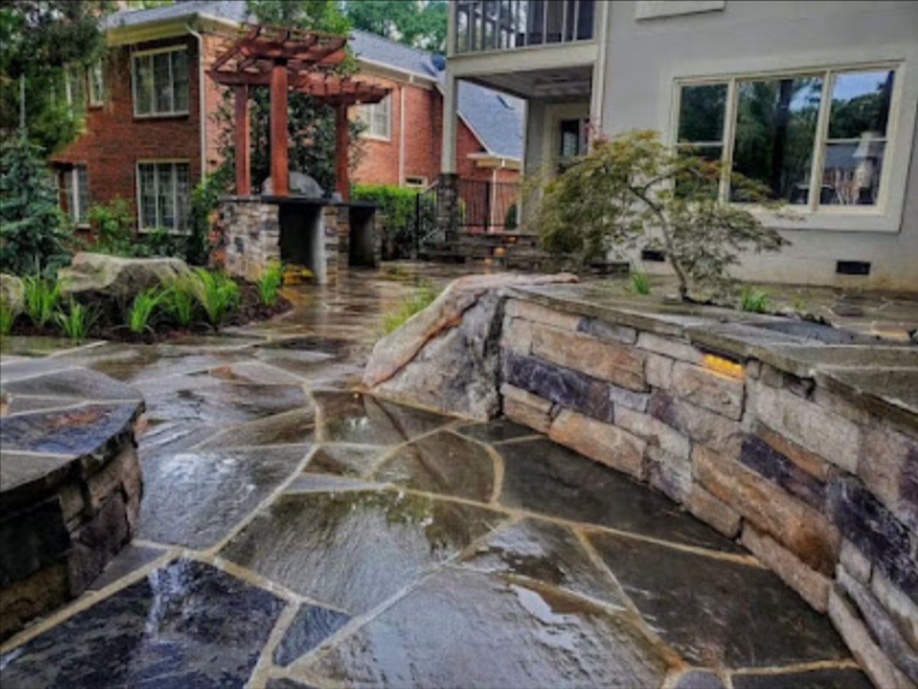 Raised stone wall and flagstone patio with young planting