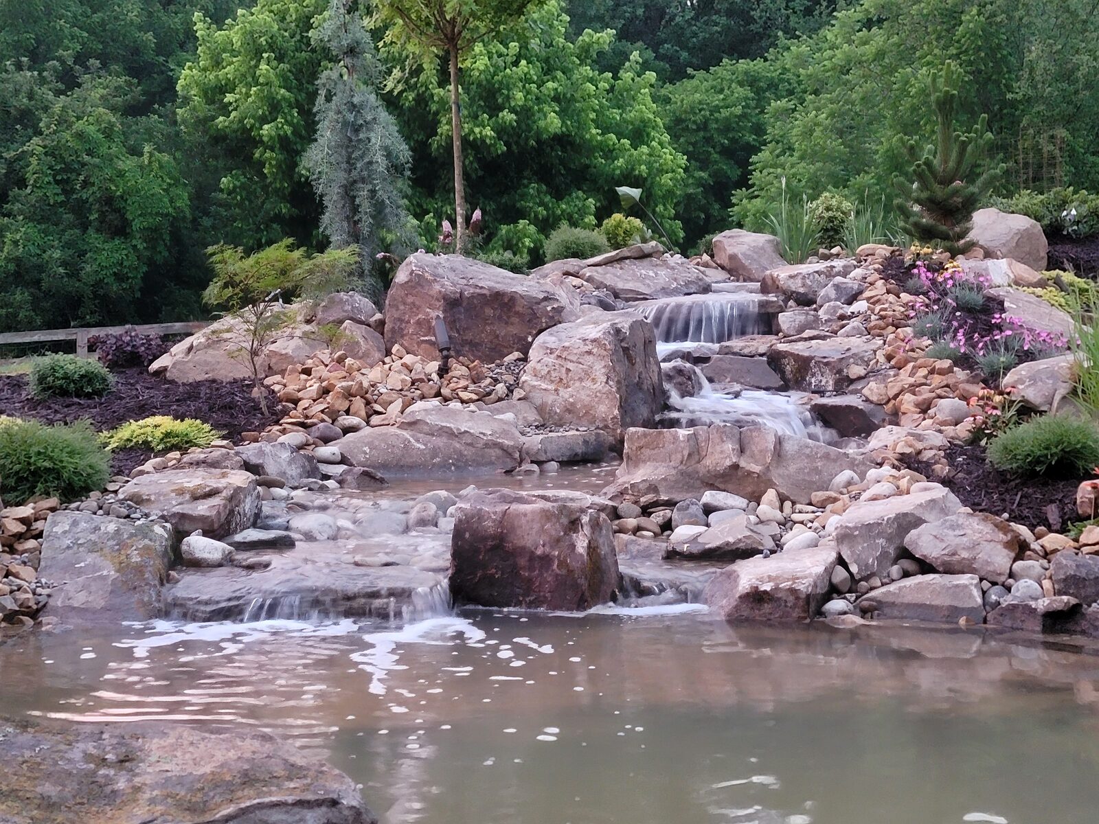 Long-exposure detail of the naturalistic waterfall's cascades beside blooming iris