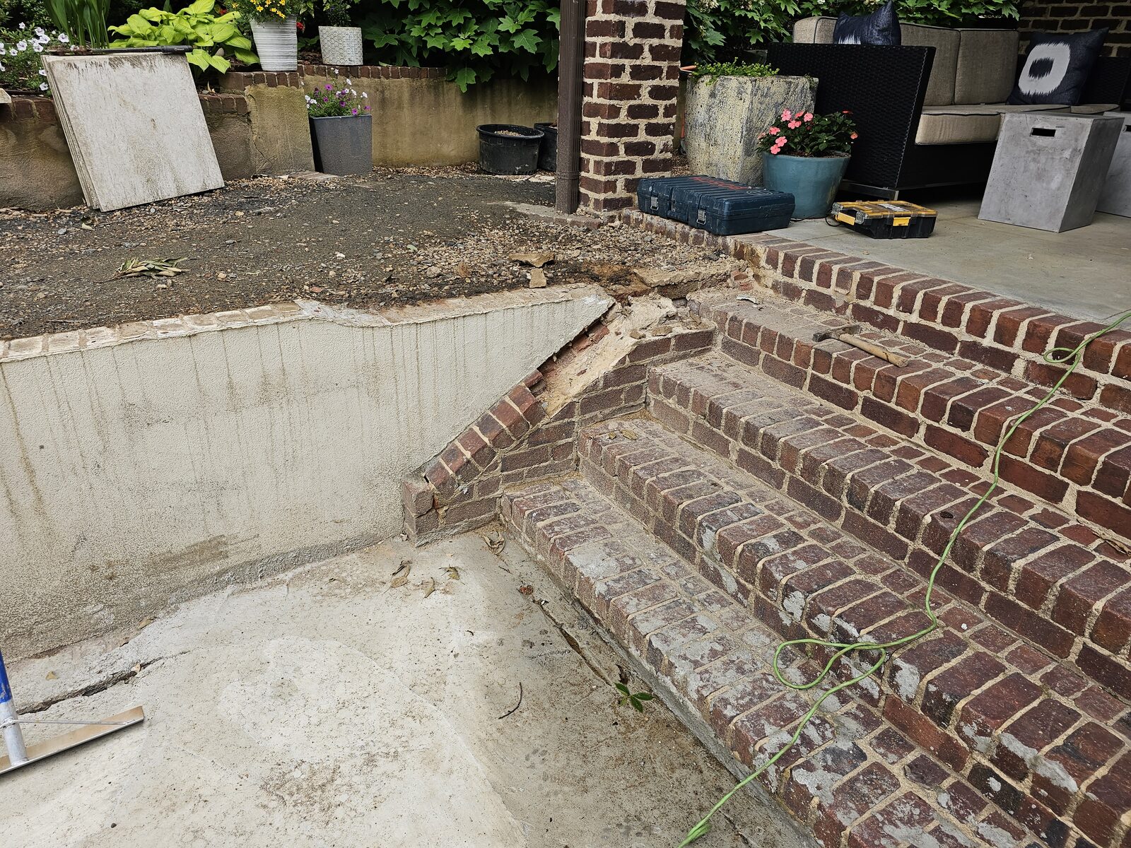 The original backyard's cracked brick steps and displaced stone during the tear-out, before the rebuild began