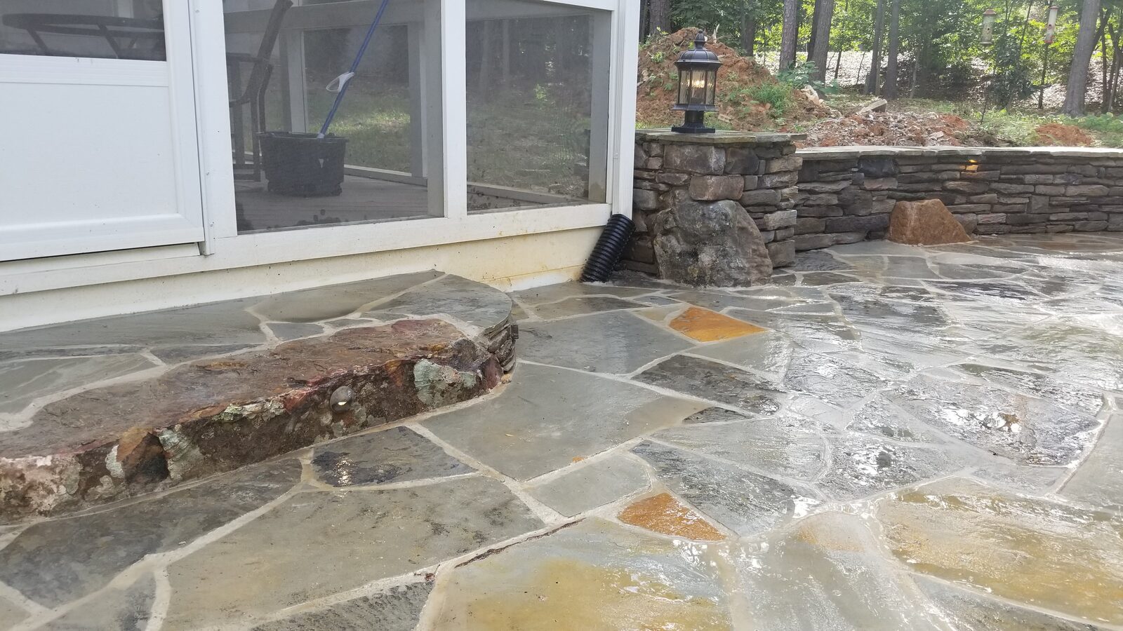 Irregular flagstone patio beside a stacked-stone pillar with a lantern-style light fixture